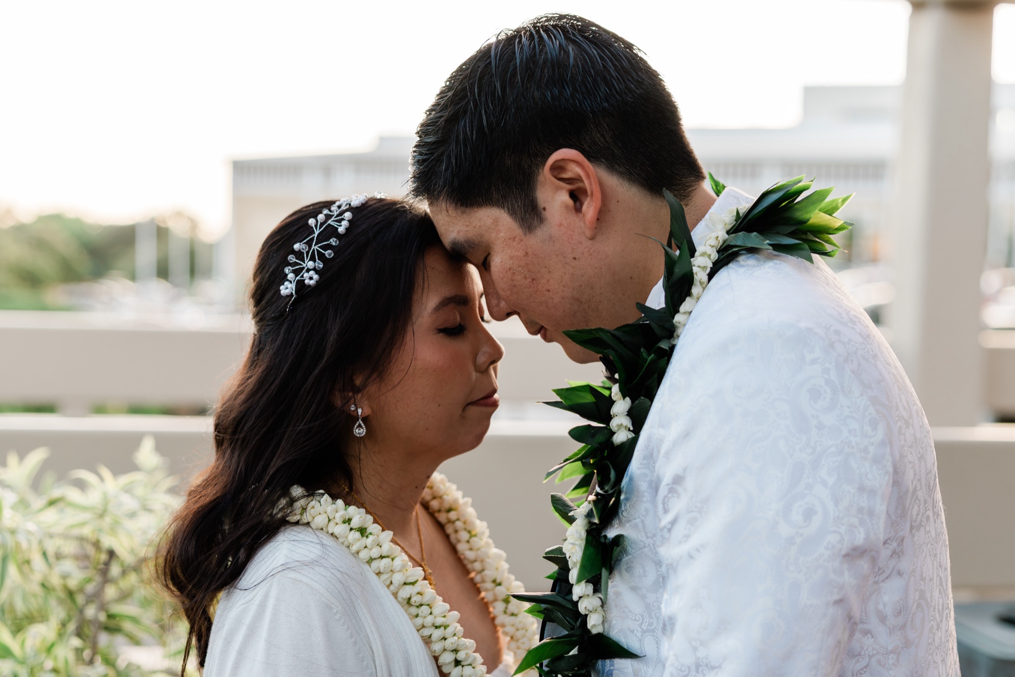 Bride and groom rest their foreheads together in golden light at their Oahu wedding